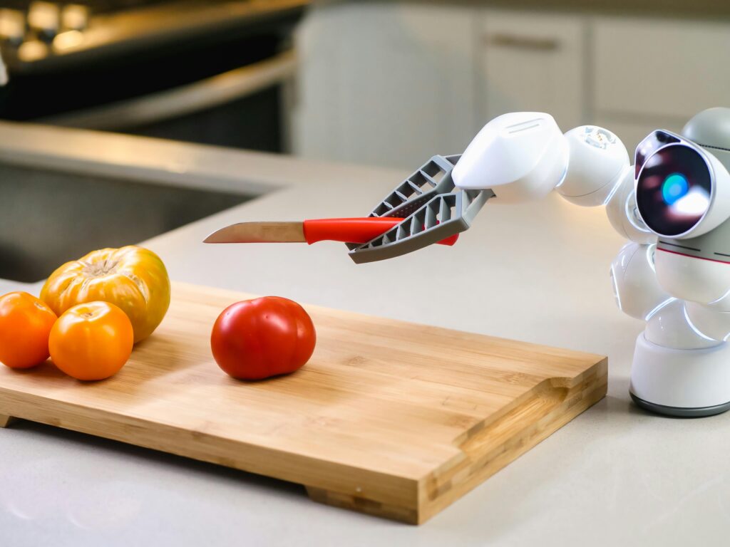 pexels-photo-9028912-9028912 A futuristic robot assists in slicing a tomato in a modern kitchen setting.